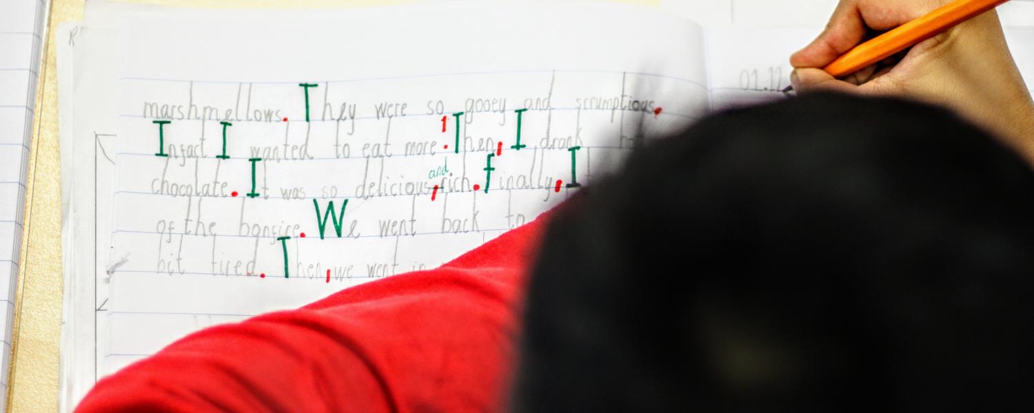 Primary student writing in workbook